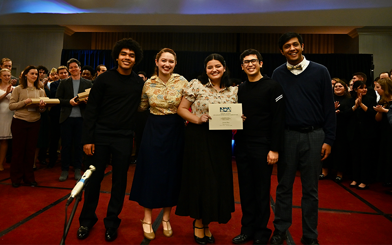 Five people posing in front of a stage.