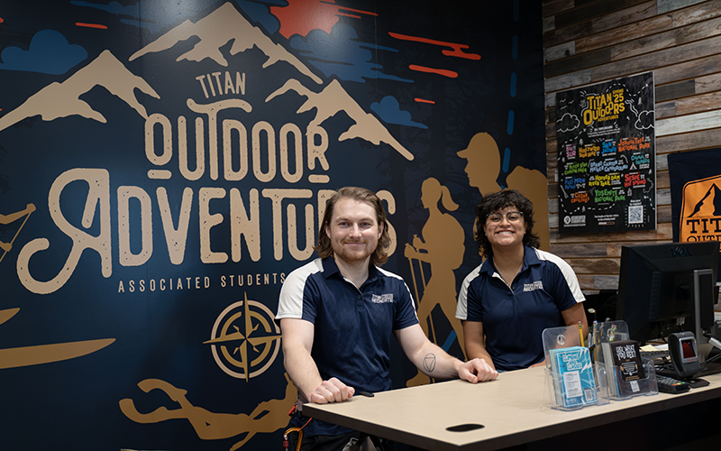 Two Titan Outdoors employees at the counter inside the rental space in the Student Recreation Center at Cal State Fullerton