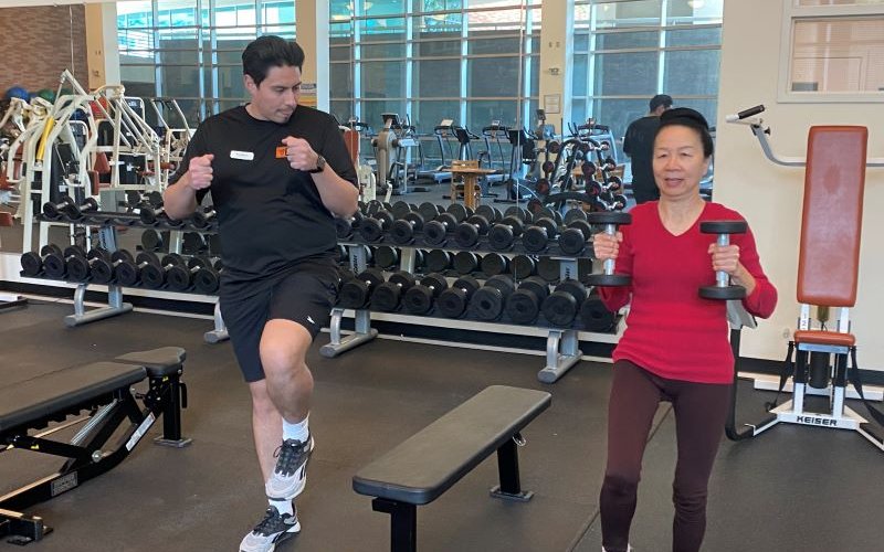 Faculty using free weights under the watchful eye of a student intern