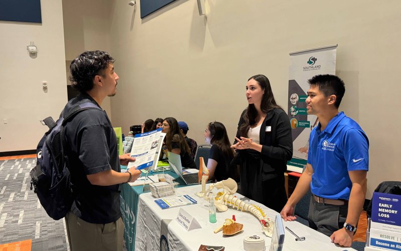 A CSUF student speaks to representatives at a table.