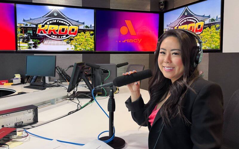 Tara Suwinyattichaiporn, CSUF associate professor of human communication studies, sits at a table with a microphone and headset at the KROQ-FM studio.