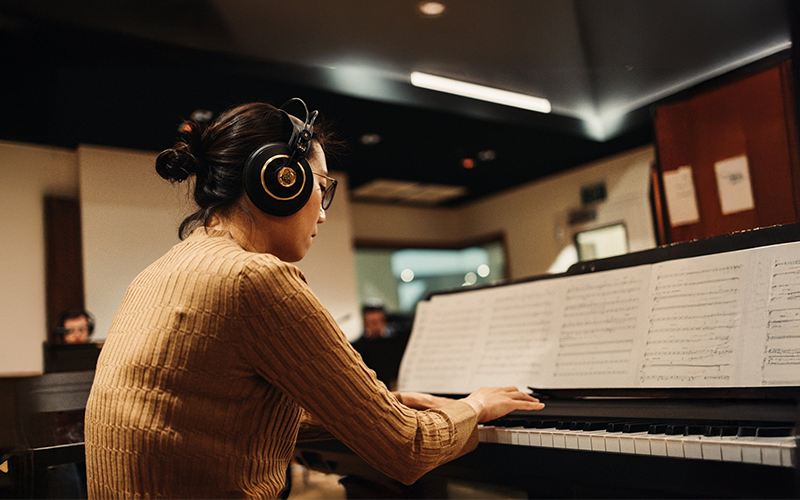 Woman at a piano turning sheet music