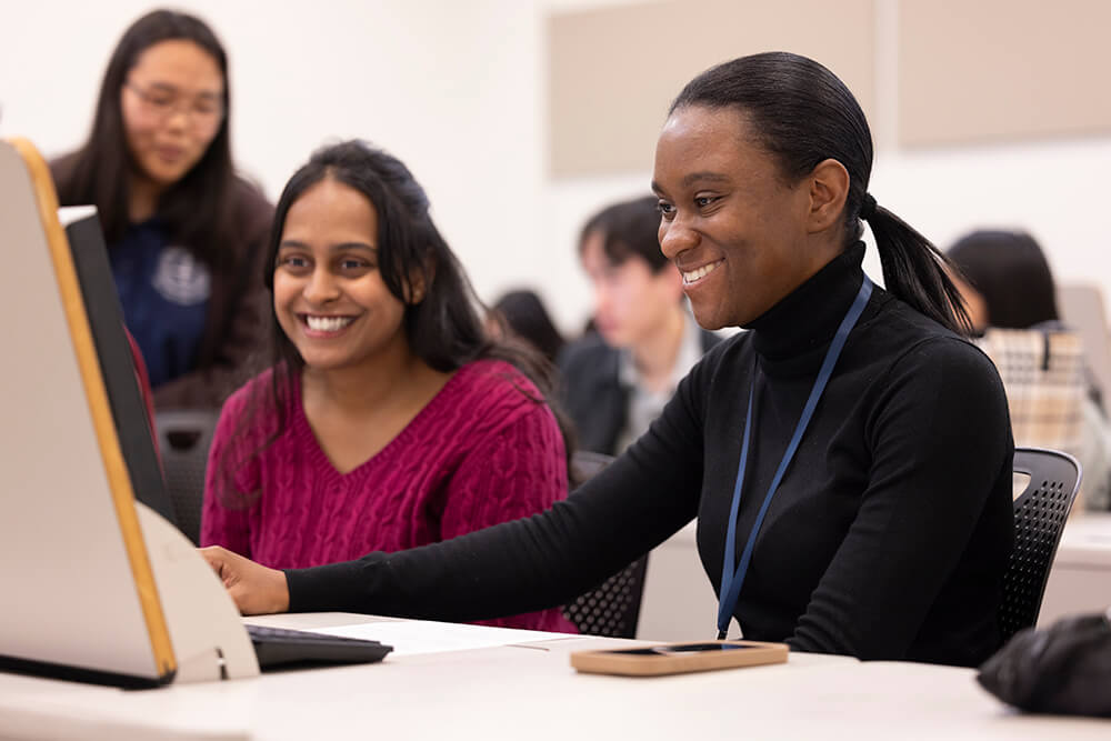 CSUF student Aish Konda works at a computer with accounting student Nyasha Davis.