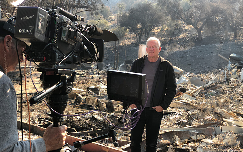 Glen MacDonald being interviewed by a camera crew in the field