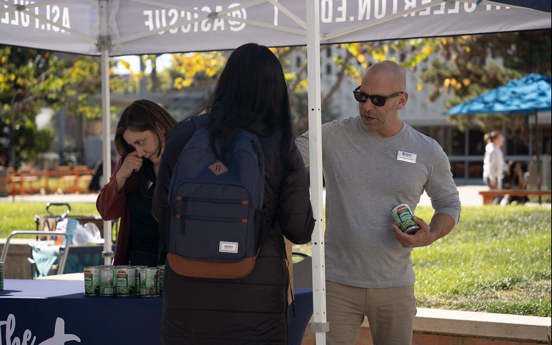 ASI Associate Director of Marketing, Communication, and Design Michael Fratino hands out food to a student visiting the November 2024 Pop-Up Pantry in the Central Quad.