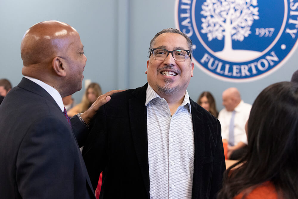 CSUF President Ronald Rochon and Alexandro Gradilla smile at an Academic Senate meeting.