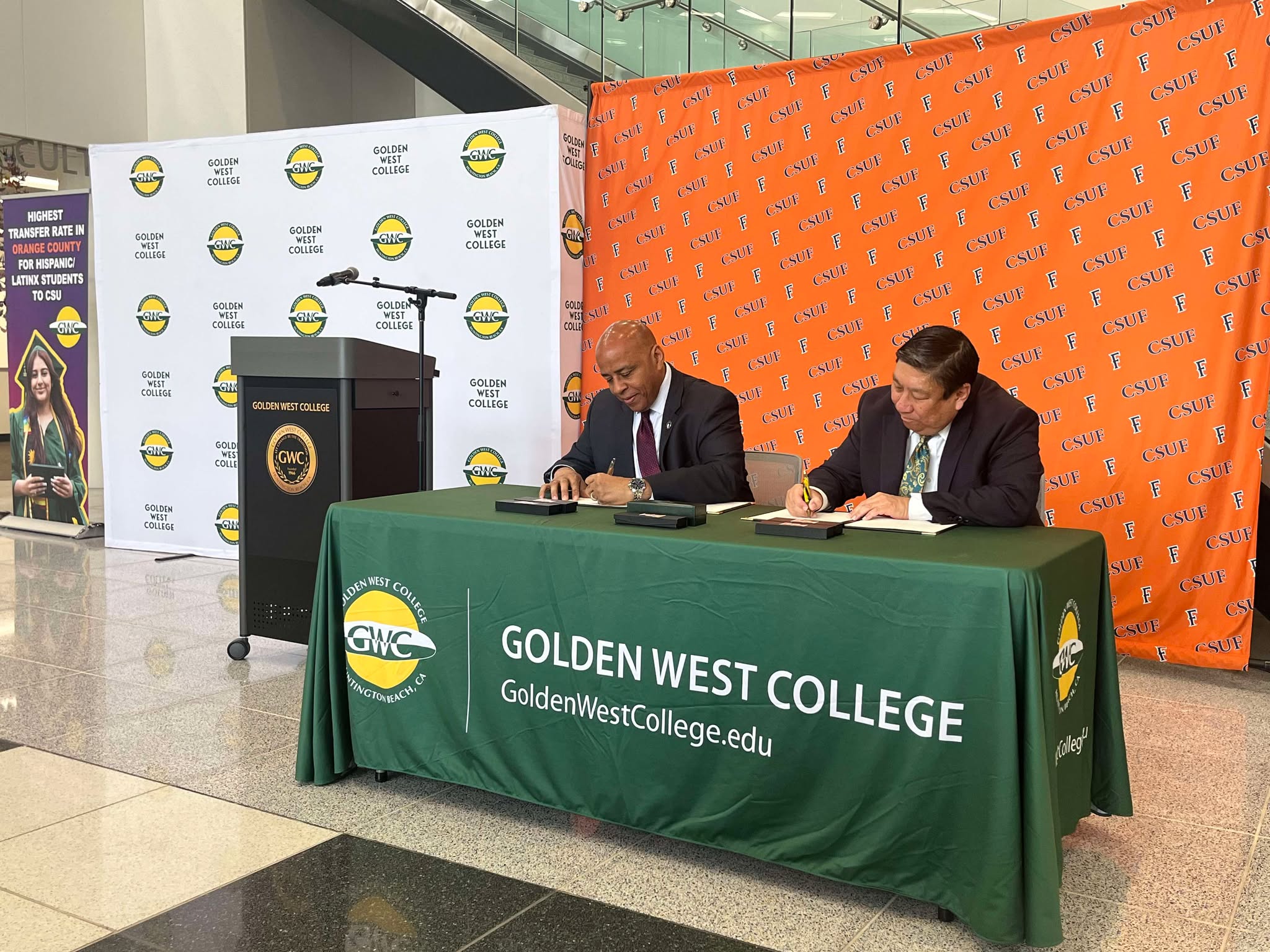 CSUF President Ronald Rochon and Coast Community College District Chancellor Whitney Yamamura sign a Memorandum of Agreement at a table.