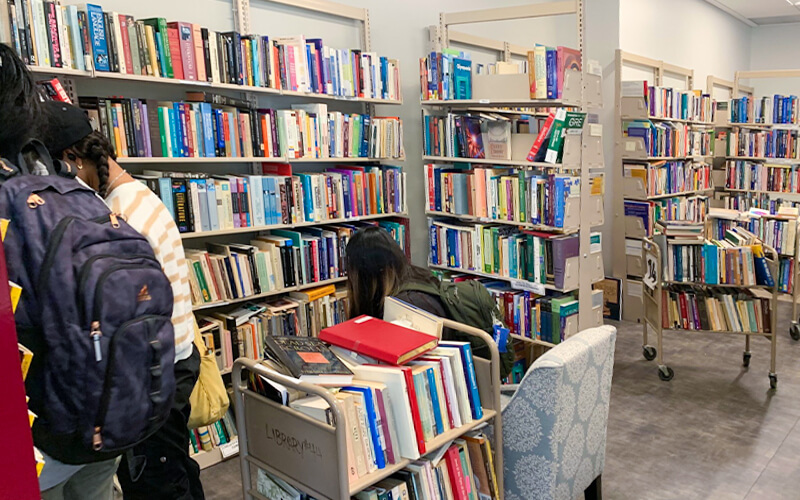 Three students browse books at the CSUF Book Sale Center.