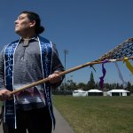 Erik Sandoval holds a wooden lacrosse stick on the intramural field.