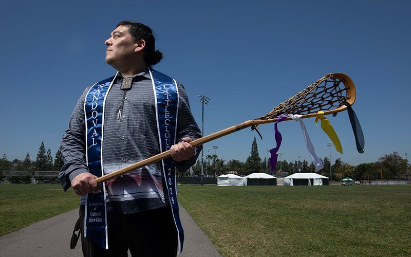 Erik Sandoval holds a wooden lacrosse stick on the intramural field.