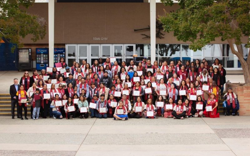 Graduating students from LA Partnership pose for a group photo outside of Titan Gym.