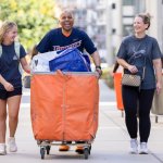 President Ronald Rochon, center, helps student Addison Grant, left, and her mother move in.