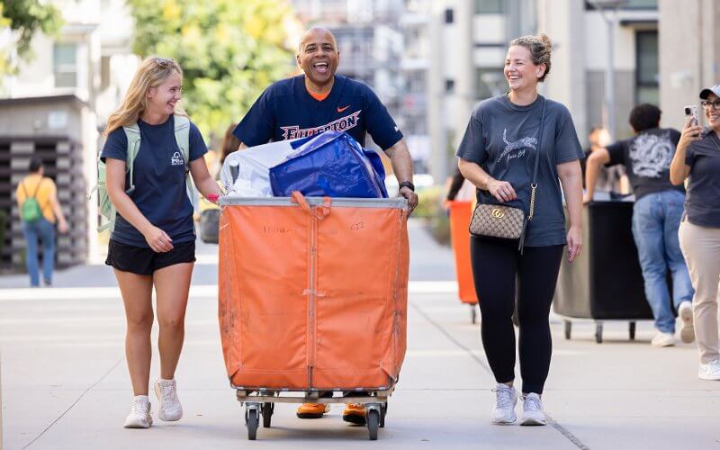 President Ronald Rochon, center, helps student Addison Grant, left, and her mother move in.