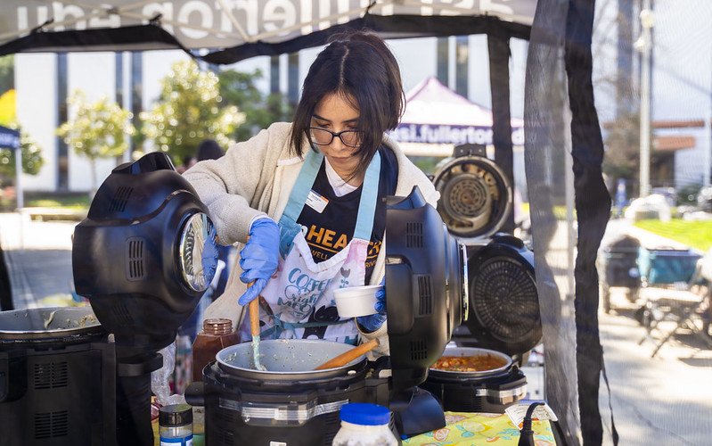 TitanWELL staff member cooks food at ASI Pop-Up Pantry.