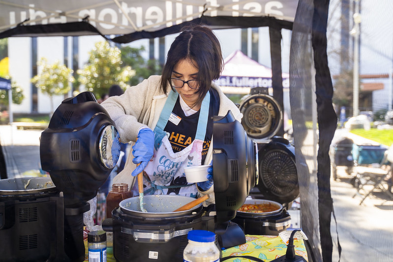 TitanWELL staff member cooks food at ASI Pop-Up Pantry.