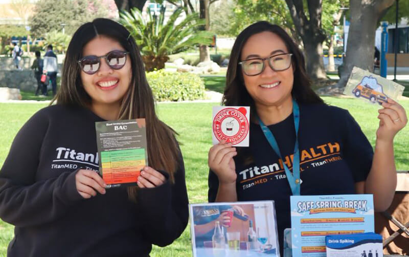 Two staff members provide information at a tabling event for National Collegiate Alcohol Awareness Week.