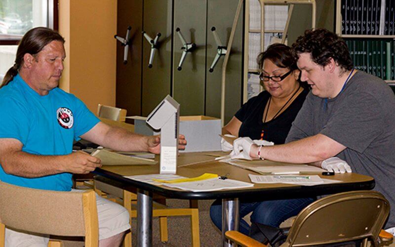 Timothy Henry-Rodriguez studies archived materials with two individuals.