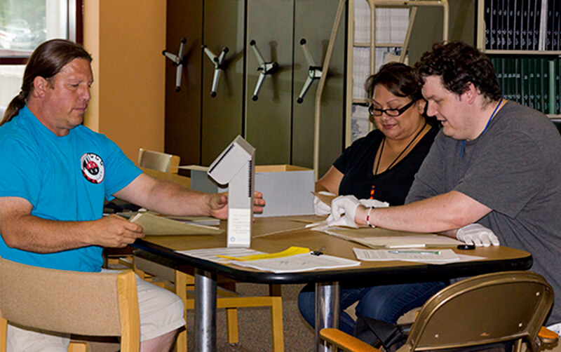 Timothy Henry-Rodriguez studies archived materials with two individuals.