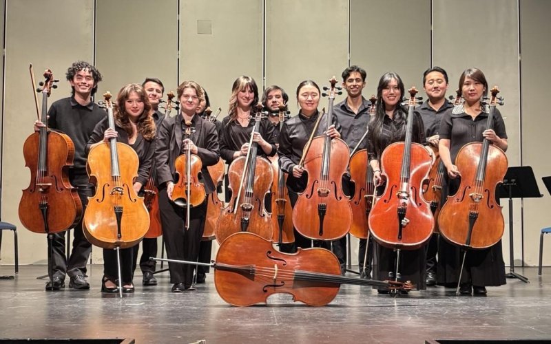 Cello students pose for a photo on stage in Germany.