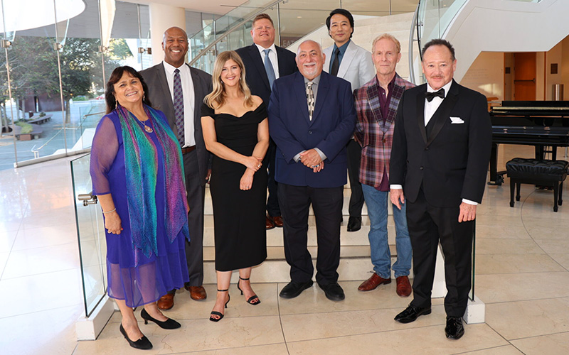 CSUF leaders and Arts Orange County members pose for a group photo in front of a staircase.
