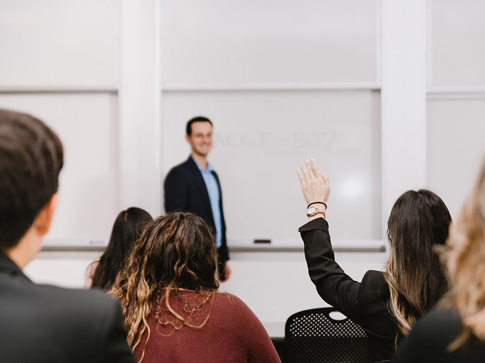 Accounting students raise their hands during a lecture.