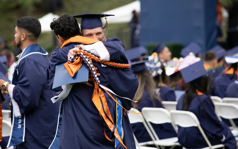 Two students hug at a CSUF commencement ceremony.