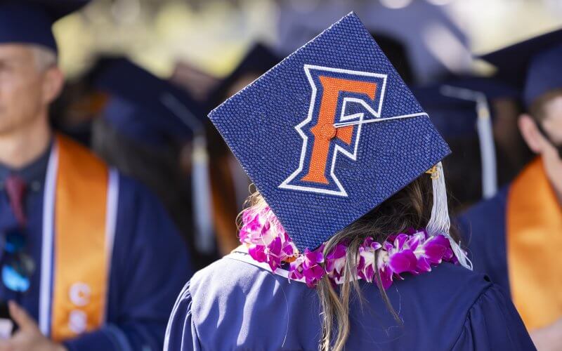 Student with commencement cap that features Fullerton "F" logo