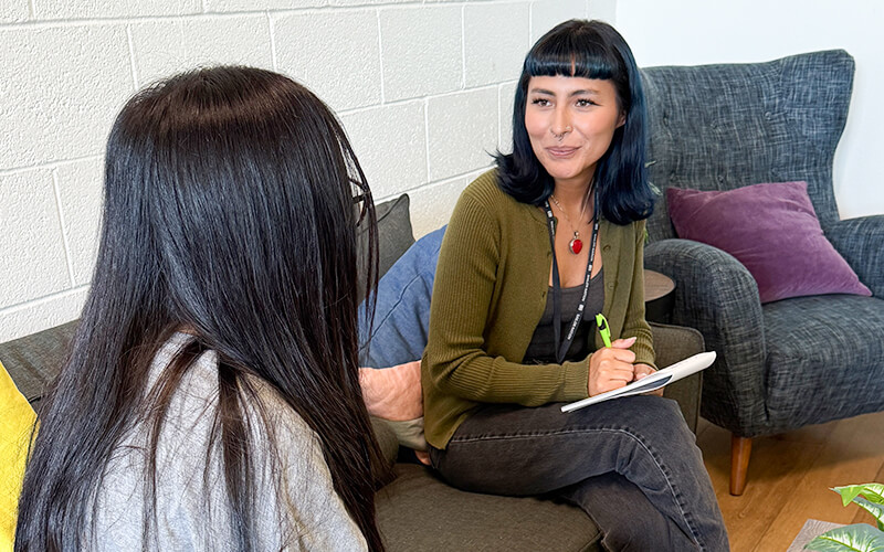 A case manager takes notes as she talks with a young student.