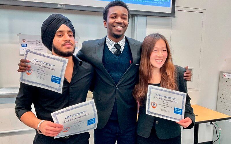 Titan Sales Competition winners Parveer Singh, Erick Redic and Dain Ko hold award certificates in a classroom.