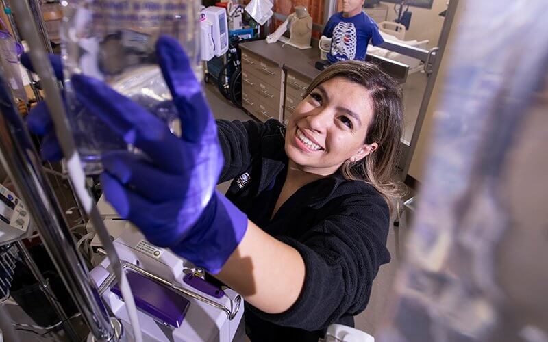 Nursing student Sophia Santana hangs a saline bag.