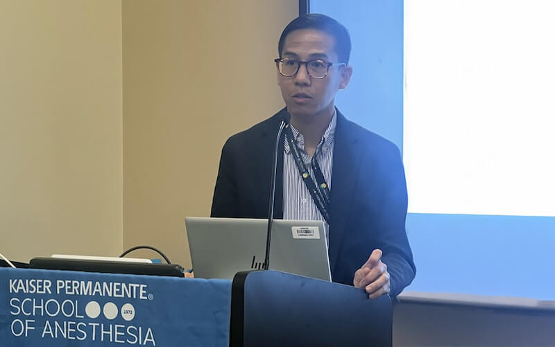 Mark Gabot stands behind a podium and delivers a lecture in a classroom.