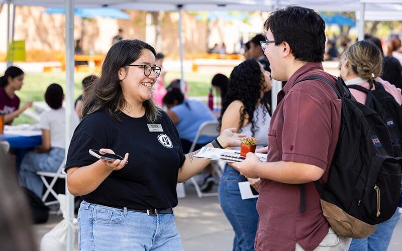 ASI student employee talks to a student on Titan Walk.