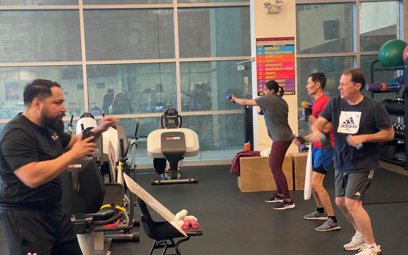 Faculty and staff members participate in an exercise class in a gym that is led by a graduate student.