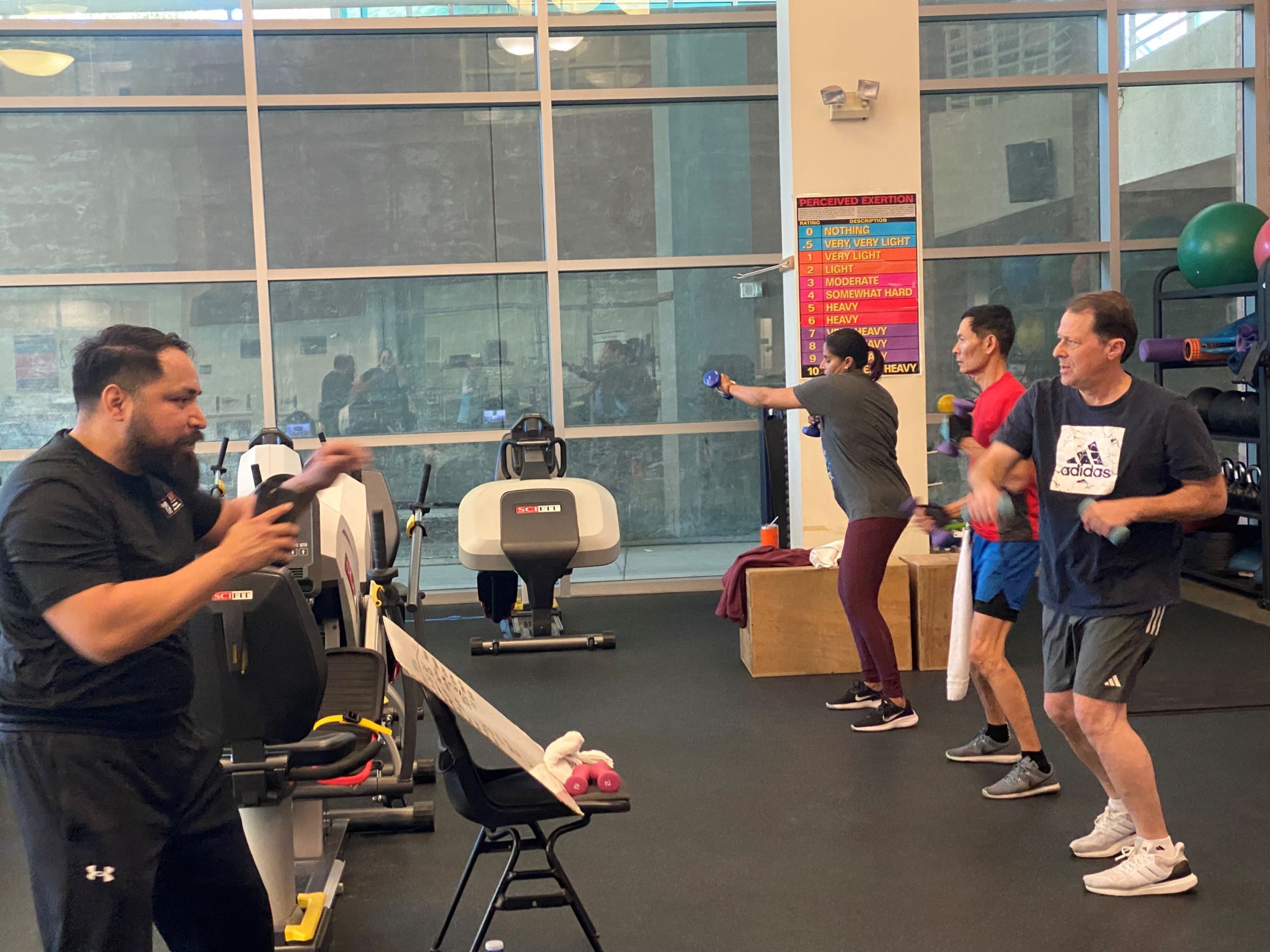 Faculty and staff members participate in an exercise class in a gym that is led by a graduate student.