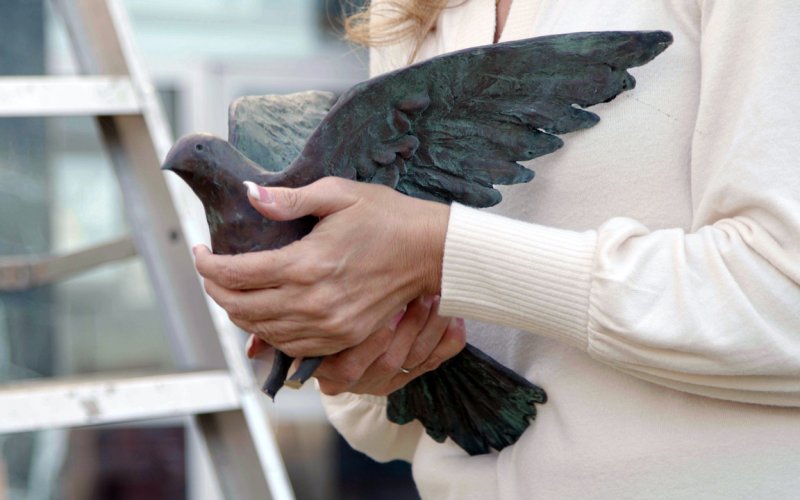 Close up image of a person holding a bronze dove statue in their hands