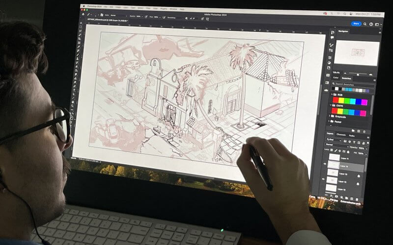 A student in a dark room works on a concept design on a large computer screen