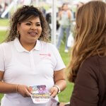 Second Start student Magaly Uriostegui holds Rotaract Club of CSUF brochure and talks to student at Discoverfest