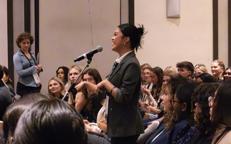 A student speaking into a microphone at the PRSSA National Conference.