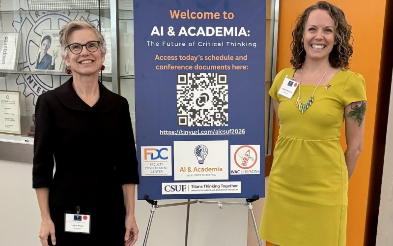Leslie Bruce and Alison Marzocchi stand in front of an "AI and Academia" conference poster