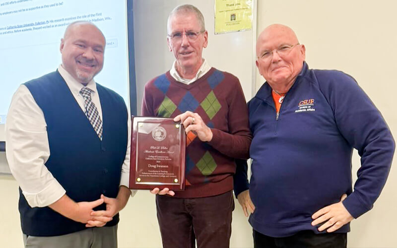 Jason Shepard, Doug Swanson and Micheal McAlexander hold an award in a classroom.