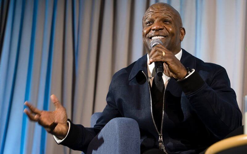 Terry Crews talks into a microphone on stage in the Titan Student Union.