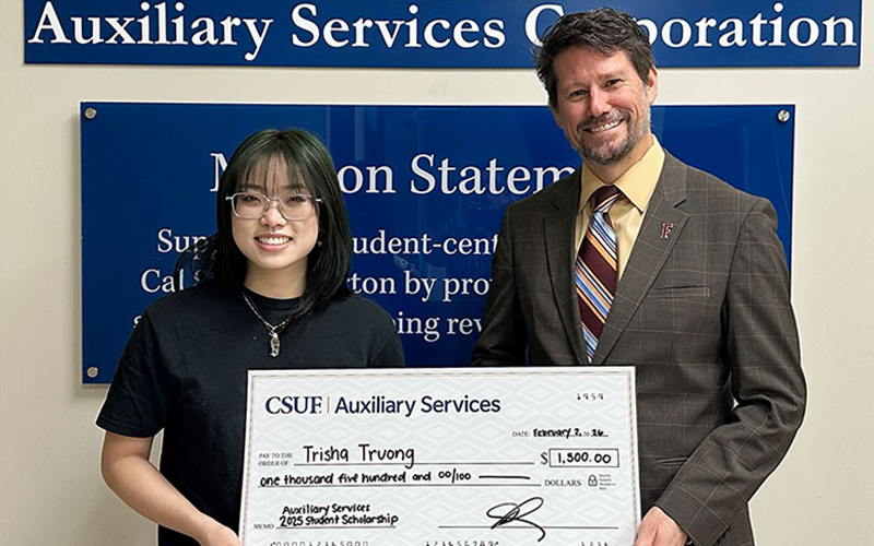 Business administration student Trisha Tran Truong is awarded a large check for the Auxiliary Services Student Employee Scholarship