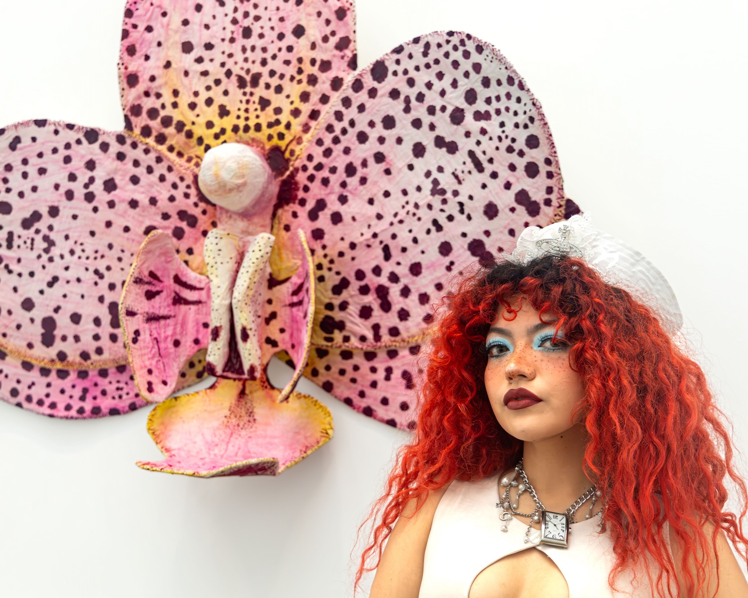 Art-teaching student Catherine “Cat” Montoya stands in front of her sculpture, "La Orquieda," which resembles a pink and maroon spotted orchid