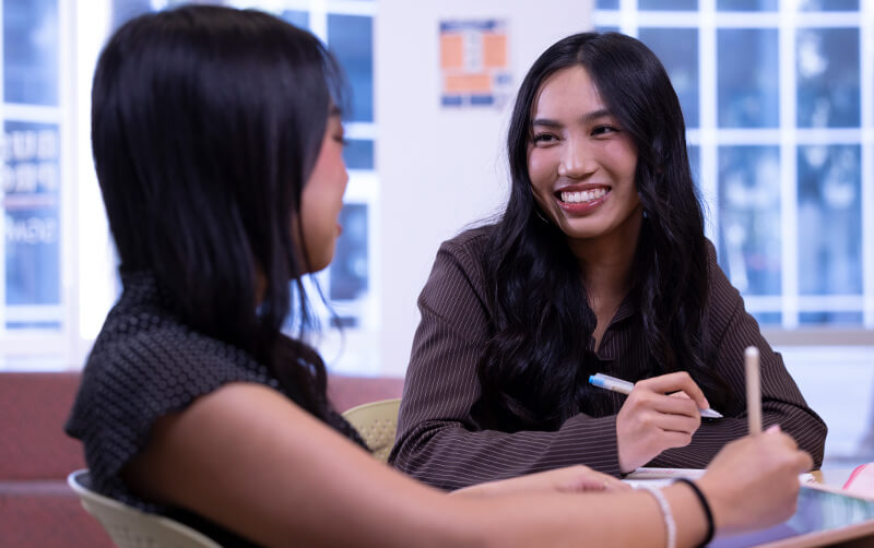 Dayna Nguyen works with another student in the Business Honors Program lounge.