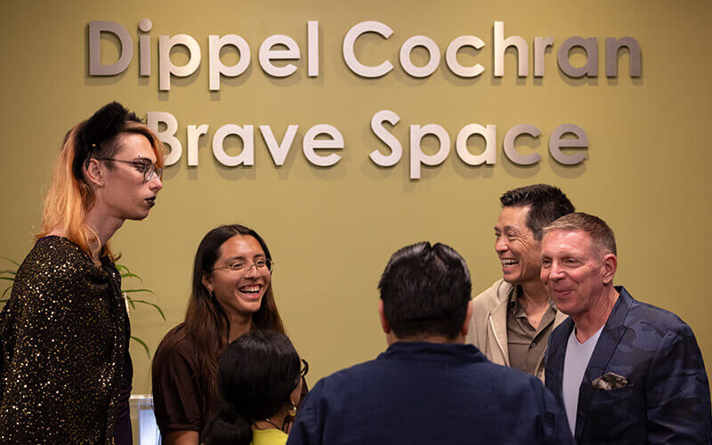 Students, donors and staff talk in front of the Dippel Cochran Brave Space sign