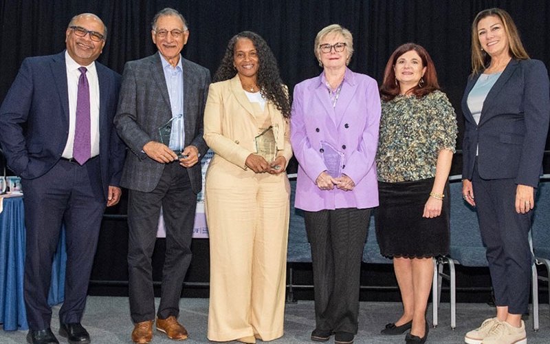 A group of people pose for a group photo on stage at CSUF's International Women's Day Conference
