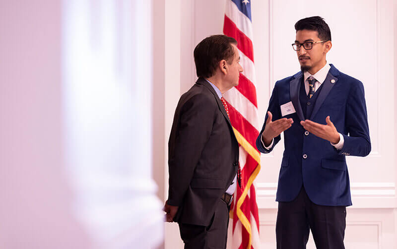 CSUF student Francis Arguien speaks with former U.S. Rep. Ed Royce at the 2026 Royce International Symposium