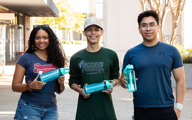 Students Jasmine Cerasuolo, Juan Rodriguez and Luis Carpio hold Amazon mentorship program water bottles