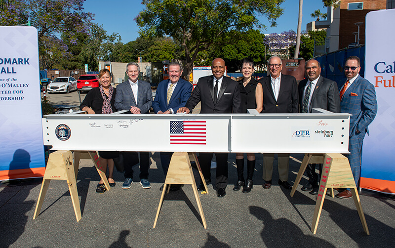 CSUF leaders and university supporters stand behind a construction beam at the April 23 Landmark Hall beam signing ceremony.