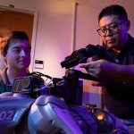 Computer science student Mason Jennings and professor Yu Bai work on a robotic dog project.
